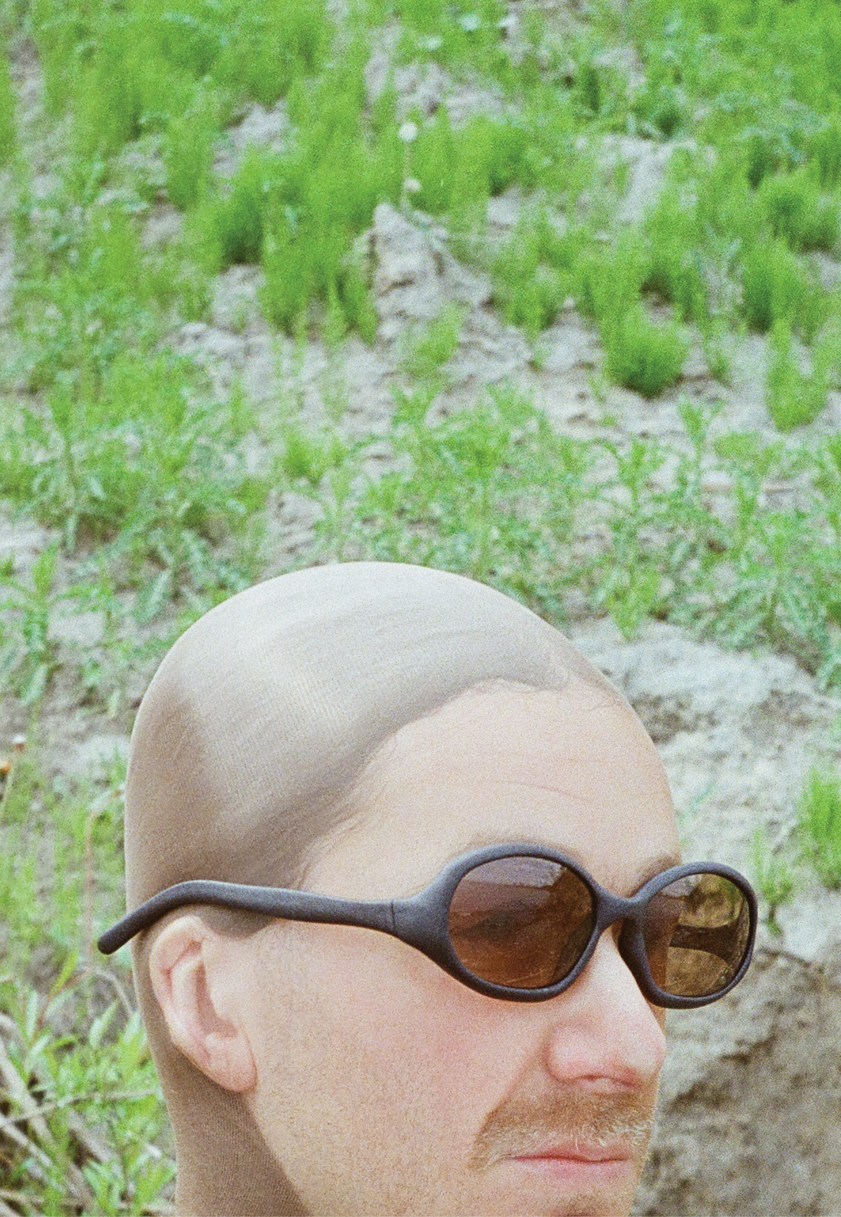 3D render of a bald model wearing black sunglasses with transparent grey lenses